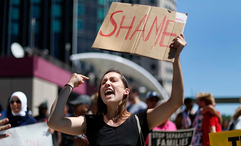 A protester holds up a sign while Republican presidential candidate Donald Trump delivers an economic policy speech to the Detroit Economic Club on Monday. AP