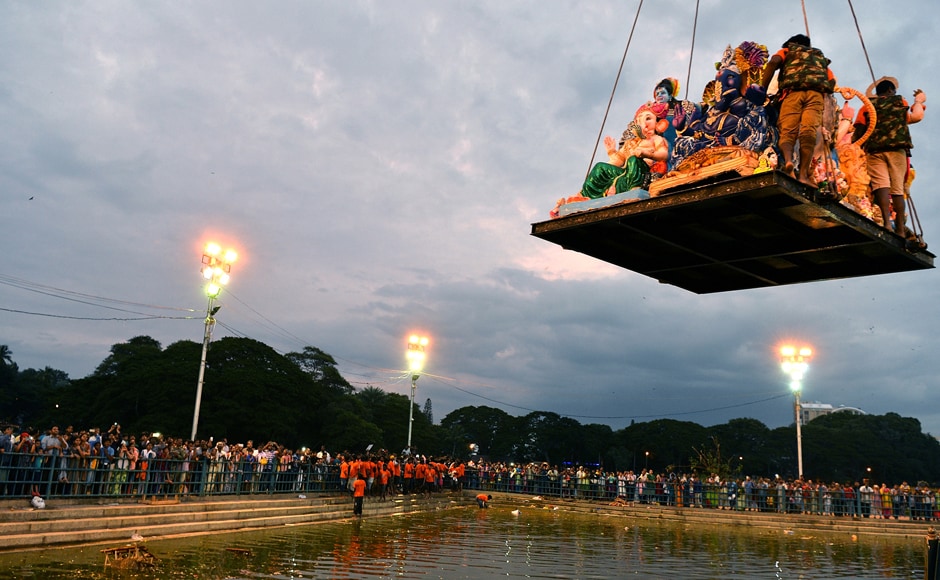 Volunteers are lowered on a platform with large idols of Ganesh brought by Hindu devotees for immersion at a water tank in Bangalore. (Photo courtesy: AFP) Volunteers are lowered on a platform with large idols of Ganesh brought by Hindu devotees for immersion at a water tank in Bangalore. (Photo courtesy: AFP)