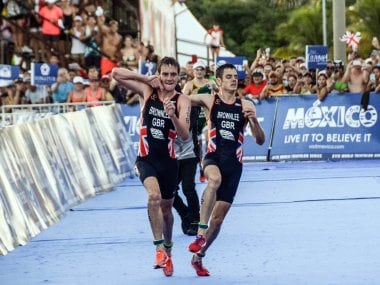 Alistair Brownlee helps his brother Jonathan Brownlee before crossing the line in second and third place during the ITU World Triathlon. AFP