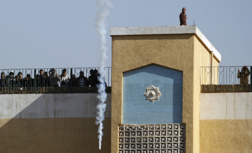 A file image of students of Al-Azhar University, supporters of the Muslim Brotherhood and deposed President Mohamed Mursi, look on from the top of a building at tear gas fired by riot police, at the university's campus in Cairo. Reuters