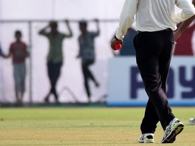 An umpire holds a pink ball as he walks during a tea break in the Duleep Trophy. AFP