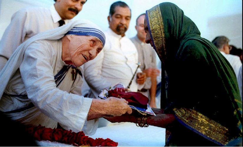 A file image of Mother Teresa presenting documents for a new house to a villager from Latur in Mumbai. Reuters