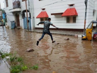 A man tries to cross a waterlogged street in Hyderabad. PTI