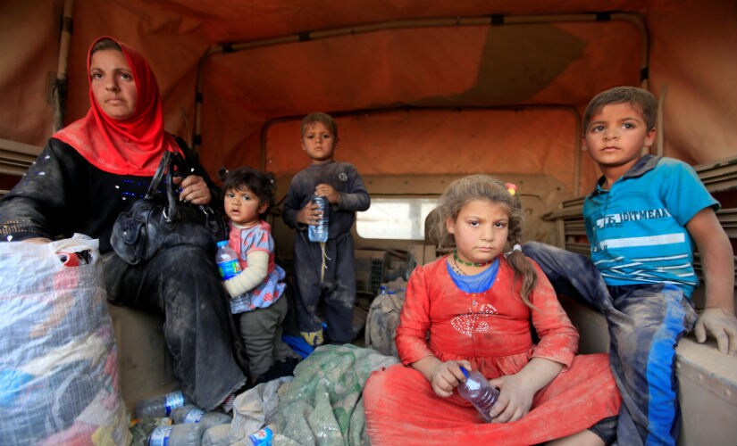 Displaced people who are fleeing from clashes sit at a military vehicle in Qayyarah during an operation to attack Islamic State militants in Mosul. Reuters