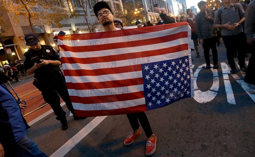 A protester carries an upside down American flag in opposition of Donald Trump's presidential election victory in San Francisco on Wednesday. AP