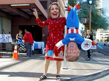 A man wears a mask depicting Democratic US presidential candidate Hillary Clinton while holding a doll depicting Republican presidential nominee Donald Trump. Reuters