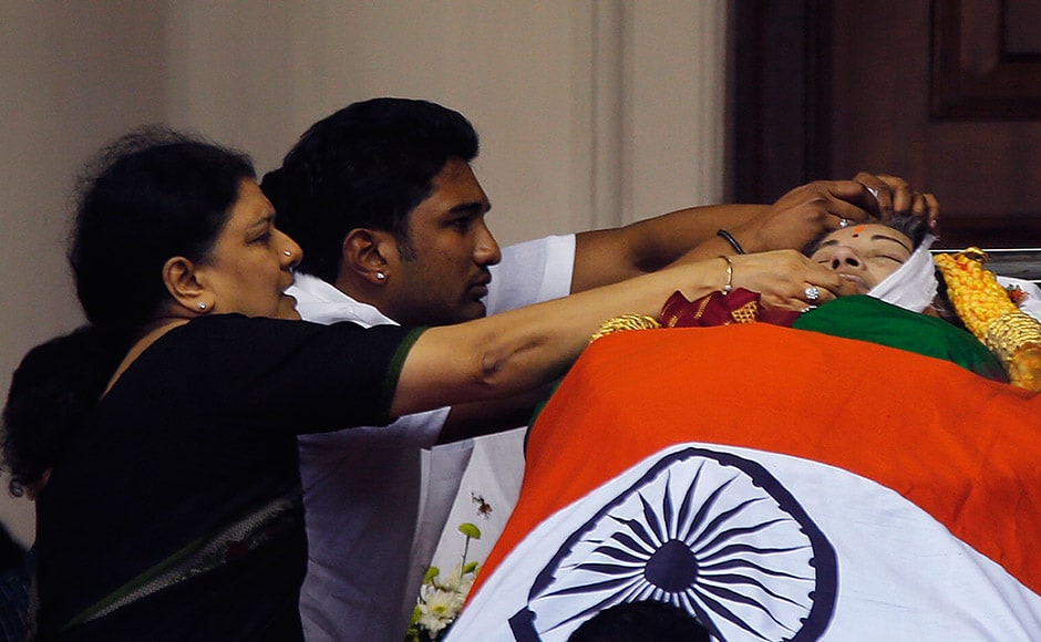 Family friends of India's Tamil Nadu state former Chief Minister Jayaram Jayalalithaa adjust a cloth around her face where her body is kept for public viewing outside an auditorium in Chennai, India, Tuesday, Dec. 6, 2016. Jayalalithaa, the hugely popular south Indian actress who later turned to politics and became the highest elected official in the state of Tamil Nadu, died Monday. She was 68. (AP Photo/Aijaz Rahi)