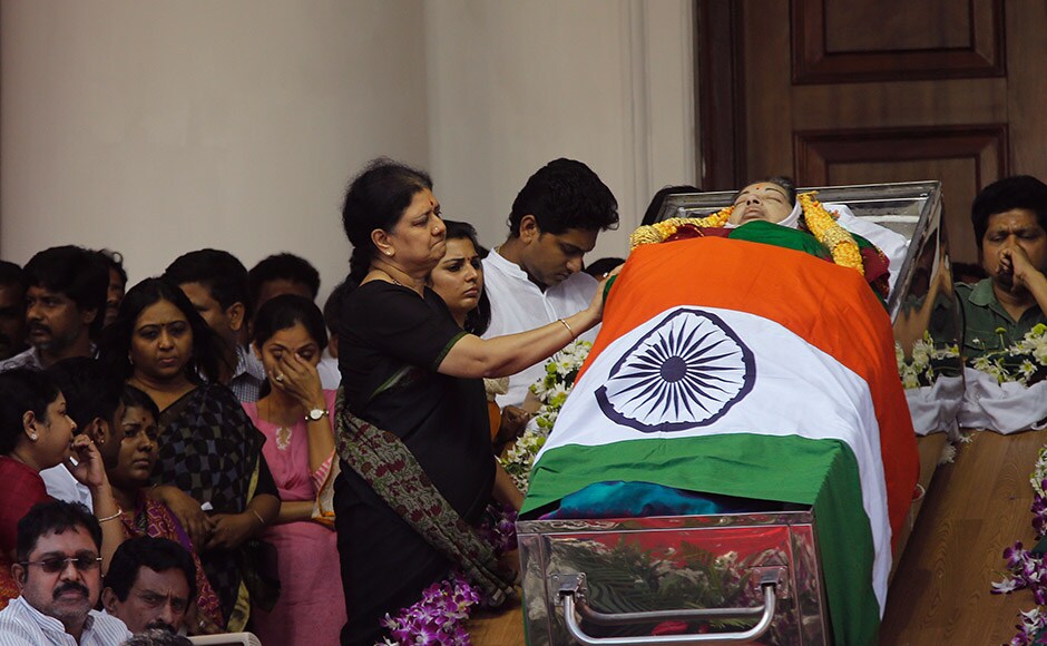 Friends of India's Tamil Nadu state former Chief Minister Jayaram Jayalalithaa grieve next to her body wrapped in the national flag and kept for public viewing outside an auditorium in Chennai, India, Tuesday, Dec. 6, 2016. Jayalalithaa, the hugely popular south Indian actress who later turned to politics and became the highest elected official in the state of Tamil Nadu, died Monday. She was 68. (AP Photo/Aijaz Rahi)