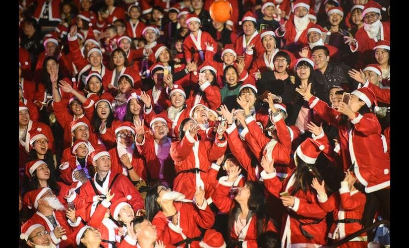People wearing Santa Claus' costumes play a game as they celebrate the Christmas Eve in Shenzhen, Guangdong province, China. AP