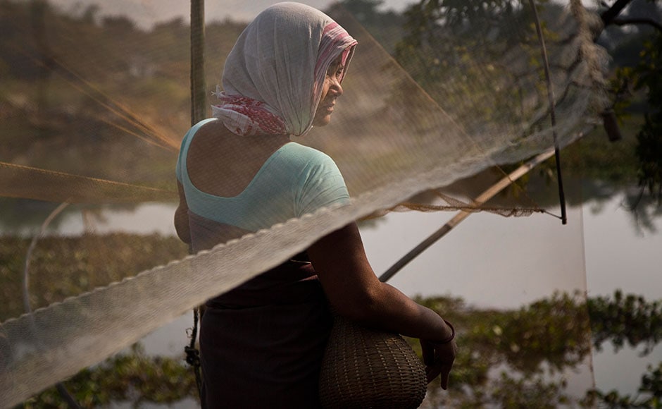 A tribal woman waits with her fishing net to participate in community fishing as part of Bhogali Bihu celebrations in Panbari village, some 50 km east of Guwahati on 13 January, 2017. A tribal woman waits with her fishing net to participate in community fishing as part of Bhogali Bihu celebrations in Panbari village, some 50 km east of Guwahati on 13 January, 2017.