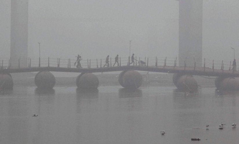 People cross the Pontoon bridge on the river Ganga amid dense fog in Allahabad on Monday. PTI