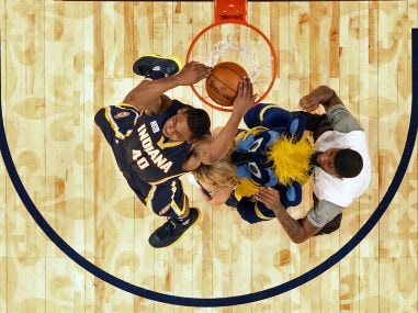 Glenn Robinson III slam dunks over teammate Paul George, a mascot, and a cheerleader. AP
