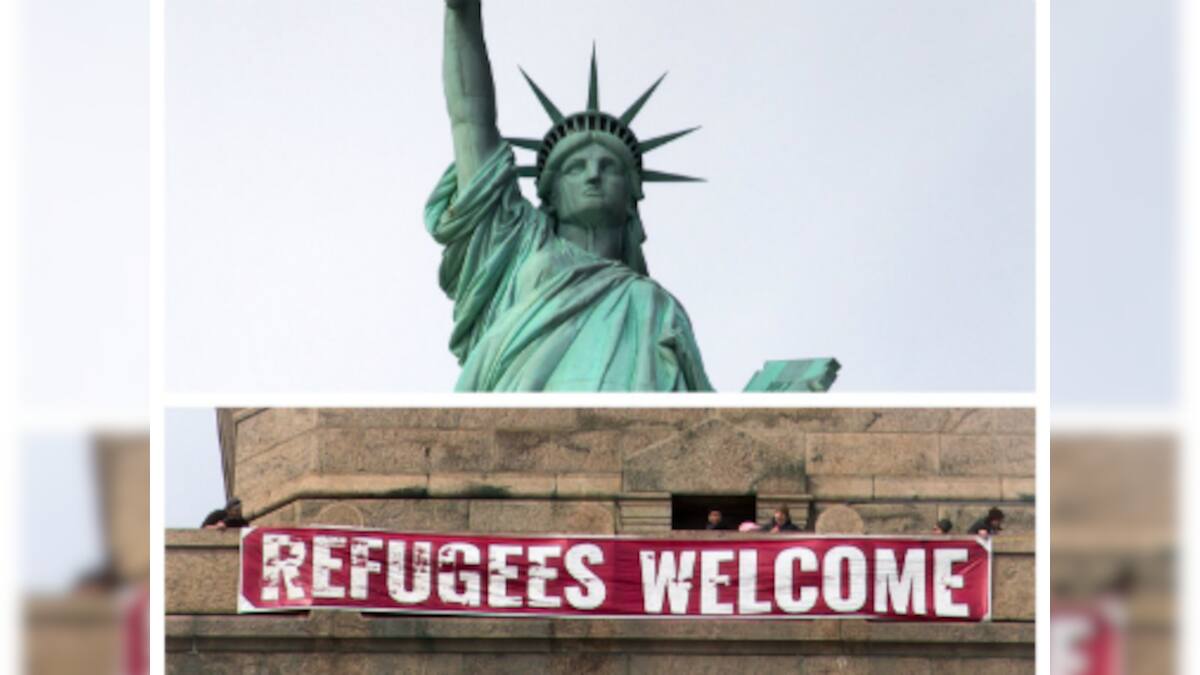 Banner reading 'Refugees unfurled atop Statue of Liberty