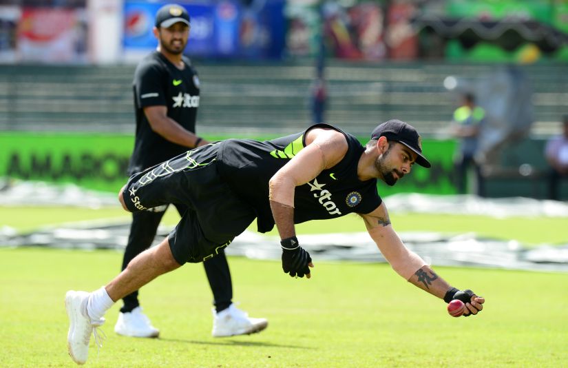 Indian captain Virat Kohli (R) is watched by teammate Karun Nair as he catches a ball during a practice session. AFP