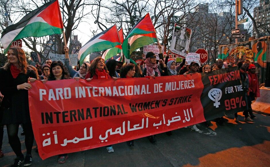 Women hold a banner along with others waving Palestinian flags as they gathered at the edge of Washington Square park before marching following a rally organized by International Women's Strike NYC, a coalition of dozens of grassroots groups and labor organizations, Wednesday, March 8, 2017, in New York. (AP Photo/Kathy Willens)