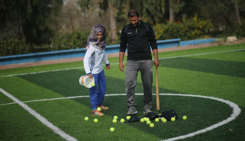 Palestinian baseball coach Mahmoud Tafesh uses a makeshift bat and tennis balls during baseball training session for women. Reuters