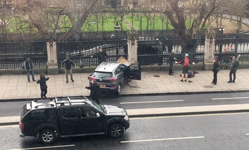 People stand near the crashed car and a injured person lying on the ground on Bridge Street near the Houses of Parliament in London on Wednesday. AP