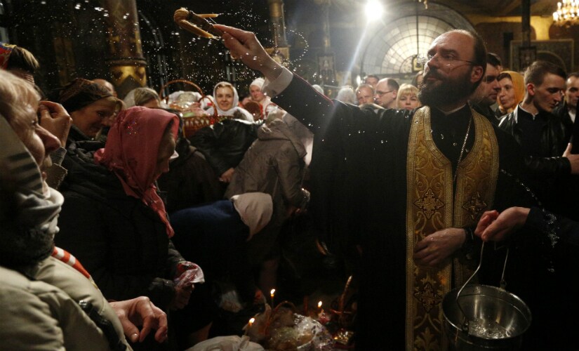 An Orthodox priest blesses traditional Easter cakes and painted eggs prepared for Easter celebrations in the Kyiv-Pechersk Lavra church, also known as the Kiev Monastery of the Caves, in Kiev, Ukraine, Sunday, April 16, 2017.