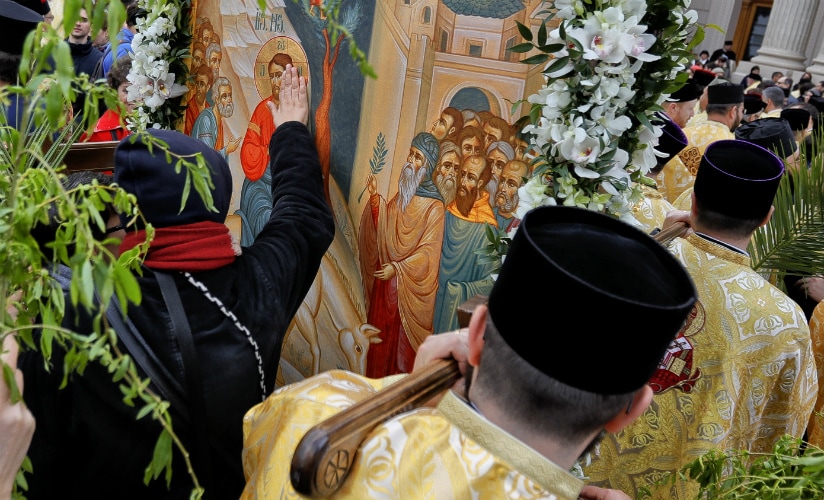 In this Saturday, April 8, 2017, picture a woman touches a large icon carried by Romanian Orthodox priests after a service ahead of Palm Sunday in Bucharest, Romania. AP
