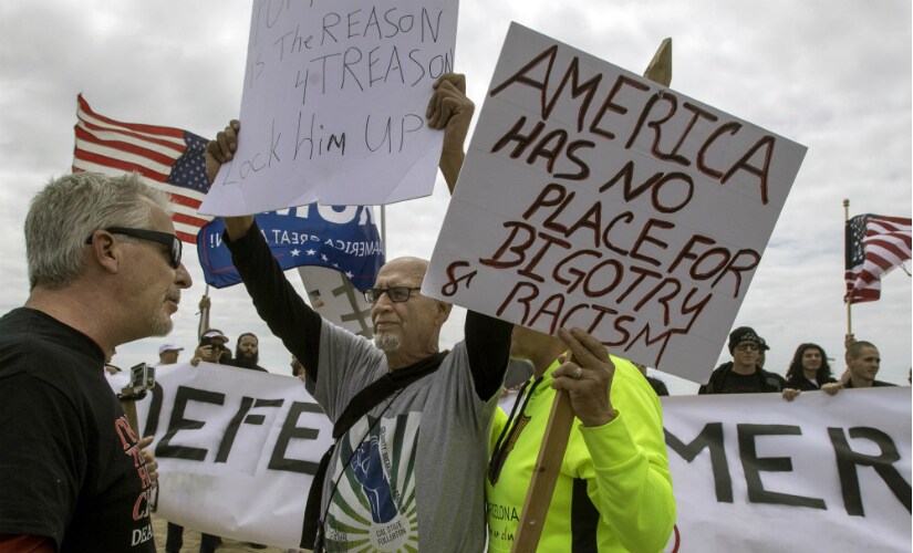 A President Donald Trump supporter, left, confronts anti-Trump protesters during a rally in Huntington Beach, Calif., on Saturday, March 25, 2017.