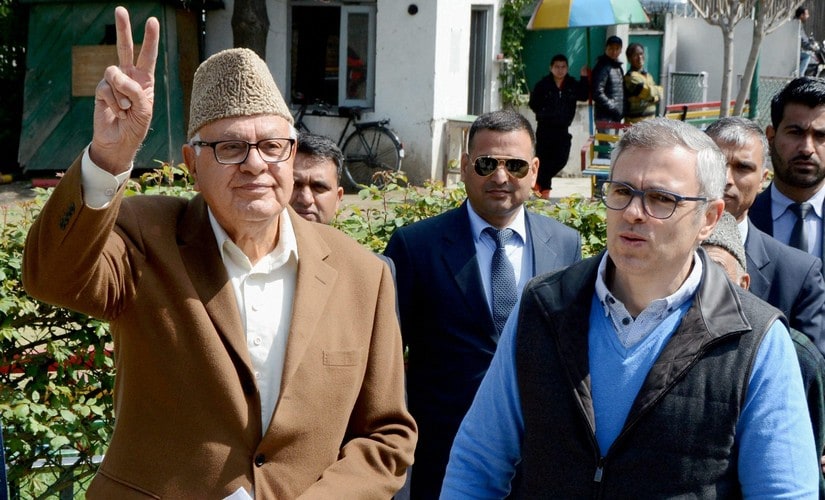 Srinagar: Former Union Minister and Congress-National Conference joint candidate Farooq Abdullah shows victory sign as his son and former Chief Minister Omar Abdullah looks on outside a polling station during voting for Srinagar parliamentary seat, on Sunday. PTI Photo (PTI4_9_2017_000085B)