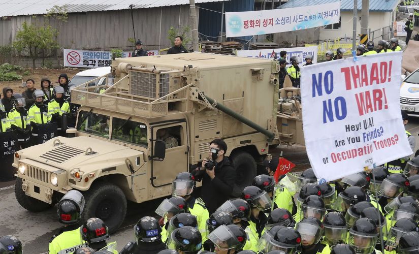 US military vehicle moves past banners opposing a plan to deploy advanced US missile defense system THAAD as South Korean police officers stand guard in Seongju in South Korea on Wednesday. AP