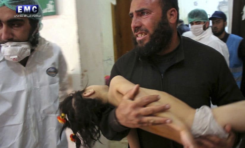 Photo provided by the Syrian anti-government activist group Edlib Media Center shows a man carrying a child following a suspected chemical attack, at a makeshift hospital in the town of Khan Sheikhoun, northern Idlib province, Syria. AP