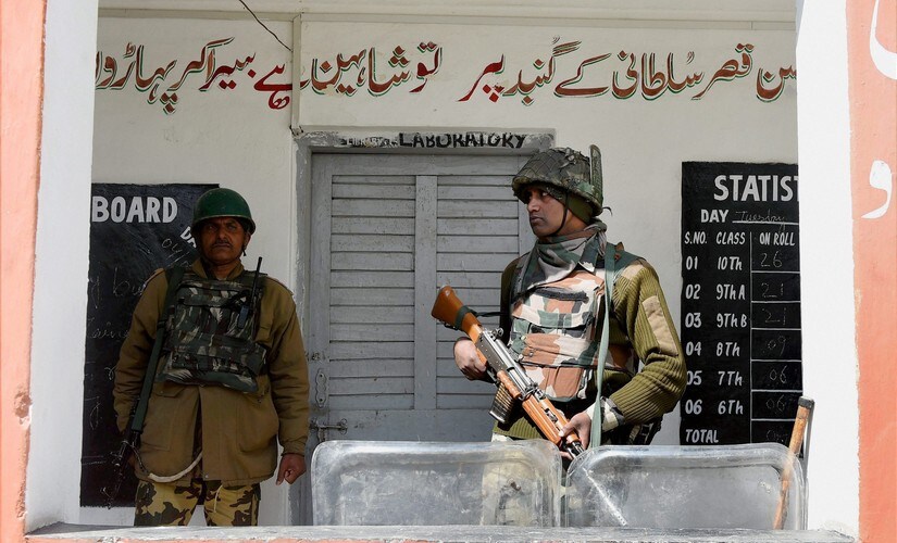 A jawan stands guard outside a polling station in Srinagar. PTI