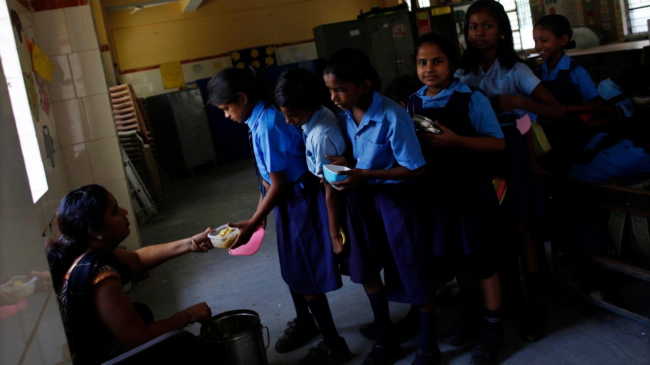 Schoolgirls collect their free mid-day meal, distributed by a government-run primary school, in New Delhi July 5, 2013. In an incident on July 16, 2013, twenty-five Indian children from a school in Mashrakh village in the district of Chapra died and dozens needed hospital treatment after apparently being poisoned by a school meal, provided under the Mid-Day Meal Scheme, sparking violent protests and angry allegations of blame. Neither the children nor the school pictured in this photograph were involved in Tuesday's poisoning incident. ATTENTION EDITORS - Neither the children nor the school pictured in this photograph were involved in Tuesday's poisoning incident. Picture taken July 5, 2013. REUTERS/Mansi Thapliyal (INDIA - Tags: FOOD EDUCATION SOCIETY) - RTX11Q07