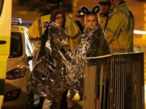 Two women wrapped in thermal blankets stand near the Manchester Arena, where U.S. singer Ariana Grande had been performing, in Manchester, northern England, Britain, May 23, 2017. REUTERS/Andrew Yates - RTX373KD