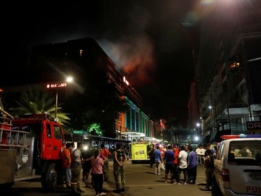 Evacuated employees watch as smoke billows from Resorts World Manila casino in Philippines. Reuters