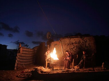 File image of a Palestinian family warm themselves up with a fire outside their makeshift house during a power cut in a poor neighborhood in Gaza. AP