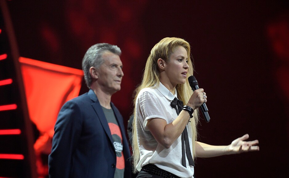 Argentinian President Mauricio Macri, left, shares the stage with singer Shakira as she speaks to the crowd during the Global Citizen Festival concert on the eve of the G-20 summit in Hamburg, northern Germany, Thursday, July 6, 2017. The leaders of the group of 20 meet July 7 and 8. (AP Photo/Jens Meyer)