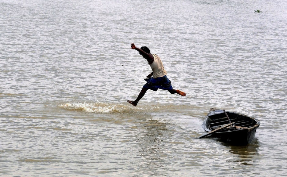 A boy jumps from his boat into the flood waters in Morigaon of Assam. PTI A boy jumps from his boat into the flood waters in Morigaon of Assam. PTI