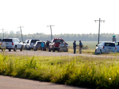 Emergency personnel stand along US Highway 82 after a military transport plane crashed into a field near Itta Bena on Monday. AP