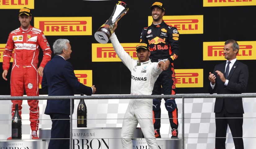 Mercedes driver Lewis Hamilton, center, jubilates while raising his trophy on the podium after winning the Belgian Grand Prix. Ferrari driver Sebastian Vettel, left, placed second and Red Bull driver Daniel Ricciardo, second right, placed third. AP