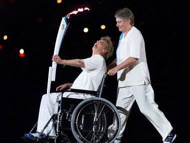 Former Australian multi-Olympic gold medallist sprinter Betty Cuthbert, who suffers from multiple schlerosis, carries the torch in a wheelchair pushed by former sprinter Raelene Boyle, during the opening ceremony of Sydney's Olympic Games September 15, 2000. Athletes from 199 nations are participating in the XXVII Summer Olympic Games which will continue until October 1. - RTXJZI9