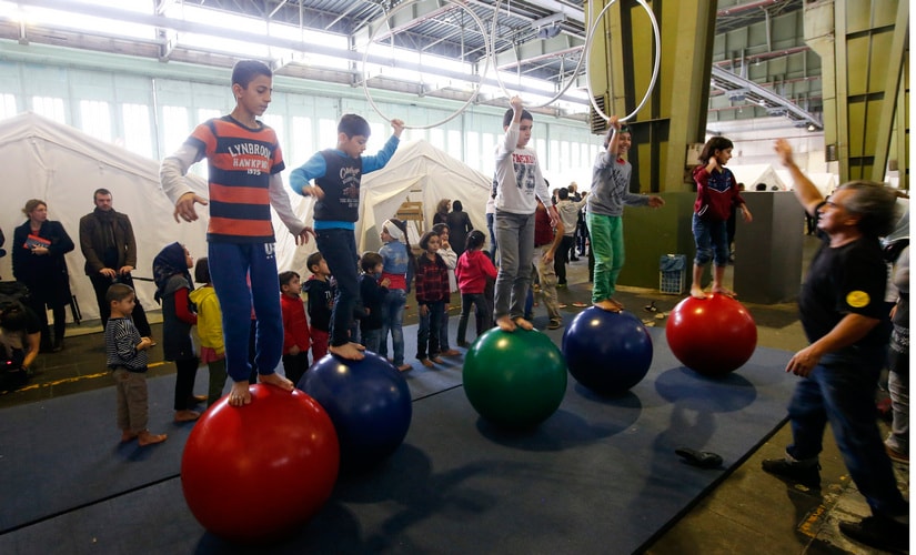 Children take part in activities with a circus performer at a shelter for migrants inside a hangar of the former Tempelhof airport in Berlin, Germany, December 9, 2015. Reuters/Fabrizio Bensch - RTX1XWRT
