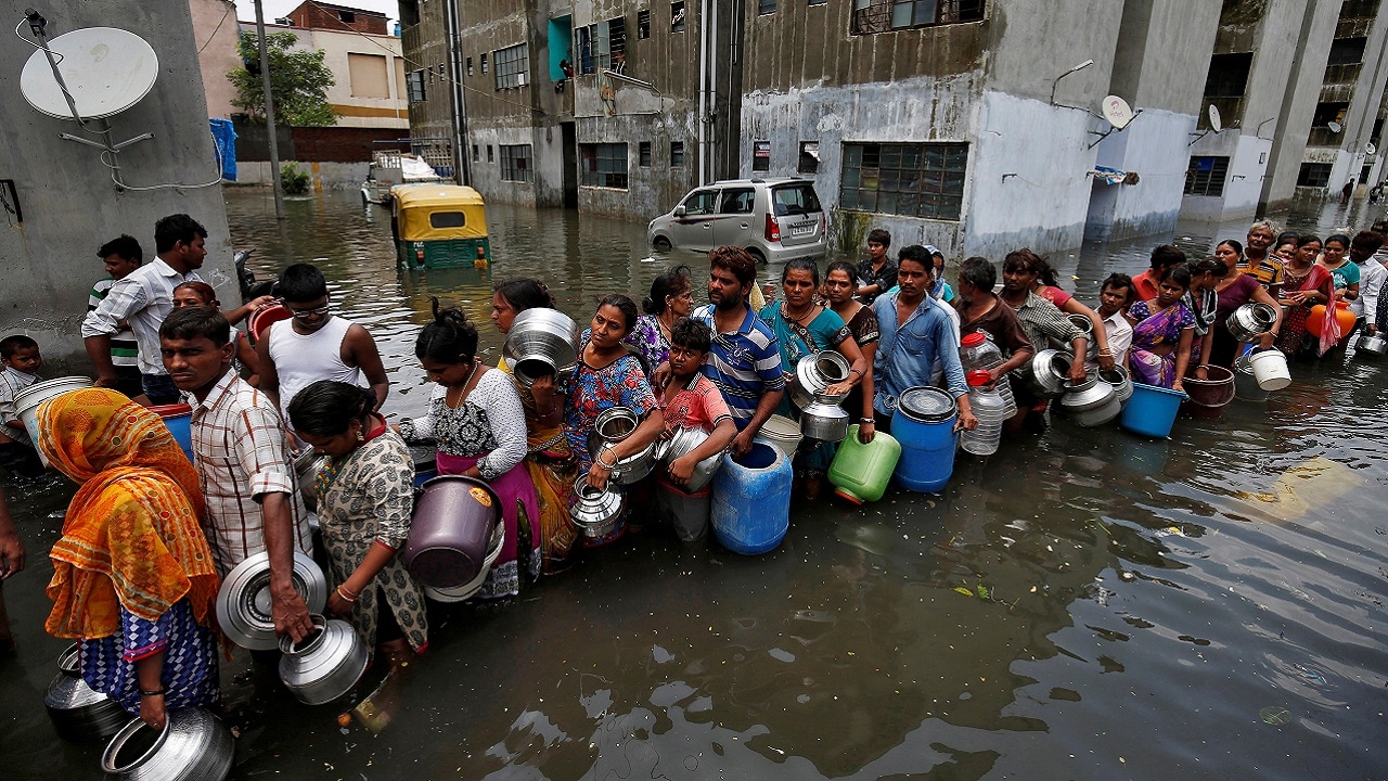 People queue to collect drinking water from a municipal tanker at a flooded residential colony in Ahmedabad, India, July 29, 2017. REUTERS/Amit Dave TPX IMAGES OF THE DAY - RTS19NNE