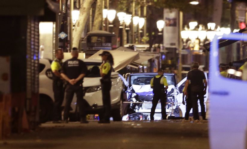 Police officers stand next to the van involved in Thursday's attack in La Rablas in Spain's Barcelona. AP