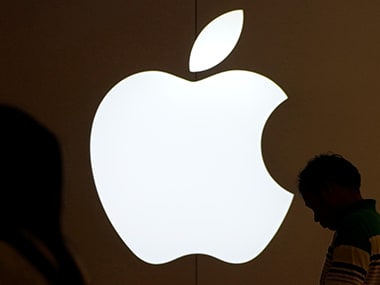 People standing in front of an Apple logo. Reuters