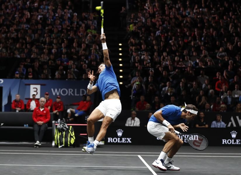 Roger Federer, right, crouches as his teammate Rafael Nadal, left, returns a ball during their doubles match. AP