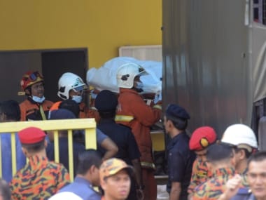 Police and firemen at the scene of the fire in Kuala Lumpur. AP