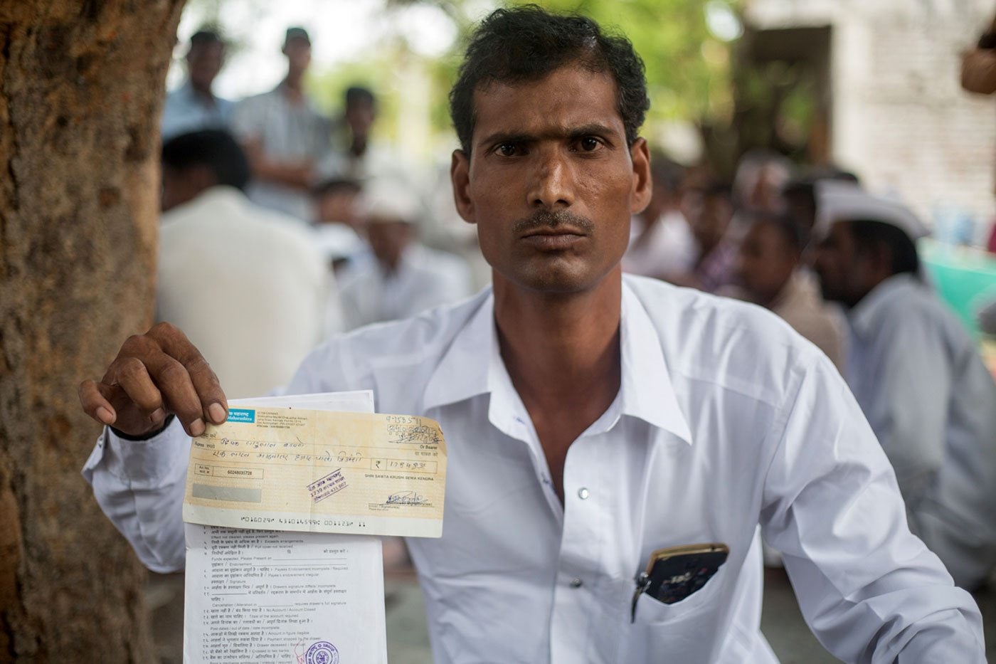 Deepak Badavne holds up the cheque he received in return for his cotton – it bounced three times. Image courtesy: Shrirang Swarge