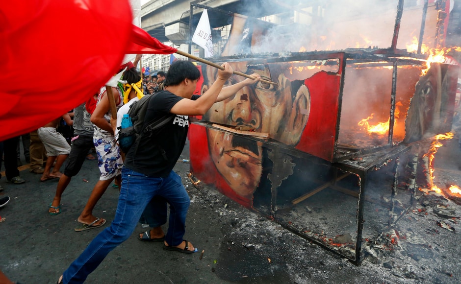 Protesters hit a burning cube effigy with the faces of the late dictator Ferdinand Marcos and President Rodrigo Duterte during a rally near the Presidential Palace to call for an end to the killings in the so-called war on drugs of Duterte and his alleged Protesters hit a burning cube effigy with the faces of the late dictator Ferdinand Marcos and President Rodrigo Duterte during a rally near the Presidential Palace to call for an end to the killings in the so-called war on drugs of Duterte and his alleged
