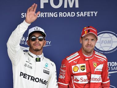 Mercedes' Lewis Hamilton celebrates his pole position alongside Ferrari's driver Sebastian Vettel, who finished 3rd but a penalty to will mean he will start in 2nd place. AFP