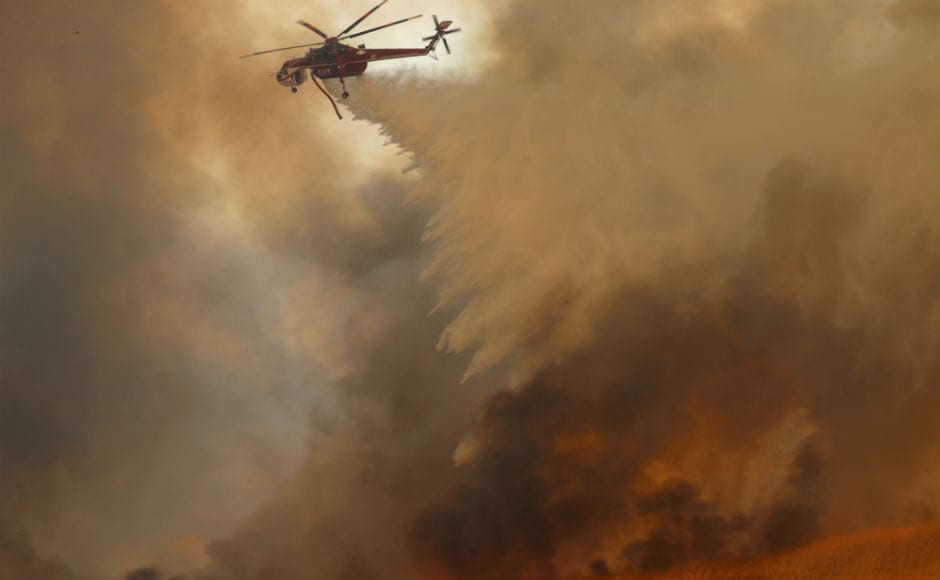 Firefighting helicopters dropped water onto burning homes as a wind-driven fire tears through neighbourhoods in Anaheim Hills. About 20,000 people have been evacuated from their homes by Monday, and additional evacuation too was carried out in several counties. Reuters Firefighting helicopters dropped water onto burning homes as a wind-driven fire tears through neighbourhoods in Anaheim Hills. About 20,000 people have been evacuated from their homes by Monday, and additional evacuation too was carried out in several counties. Reuters
