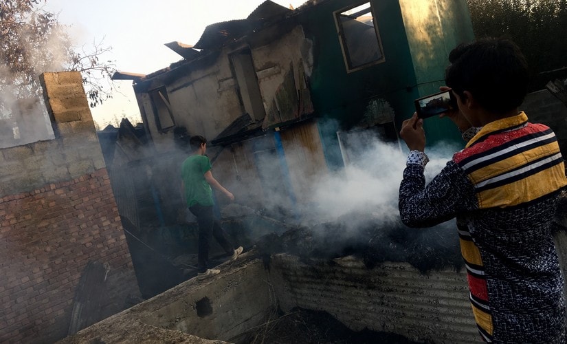 A child takes pictures of burnt house of Mohammad Ramzan Sheikh. A steel trunk, few half-burnt clothes and some charred utensils is all that remains of Sheikh’s house. Sameer Yasir/Firstpost