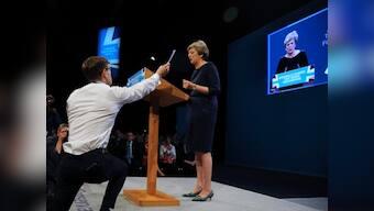 Theresa May tries to rally Conservatives, but gets interrupted by protests, coughing fit, and collapsing set