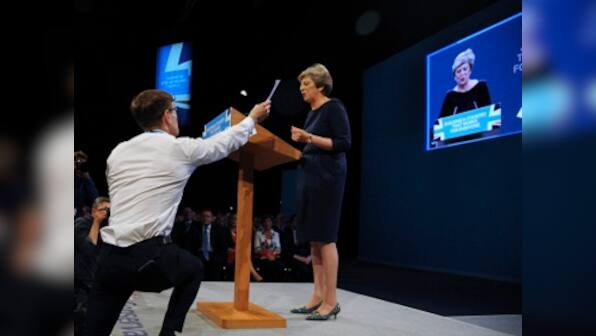 Theresa May tries to rally Conservatives, but gets interrupted by protests, coughing fit, and collapsing set